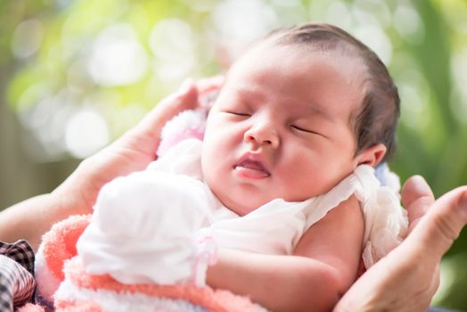 Newborn baby sleeping in mother's hands, selective focus in her eyes, Family concept