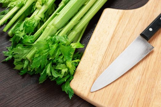 Bunch of fresh celery stalk on wooden table and cutting board and knife with leaves. Food and ingredients  of healthy vegetable. Freshness herbal and low calories for dieting with plenty of vitamin