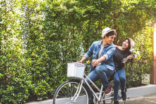 Happy couple riding bicycle together in romantic view park background. Valentine's day and wedding honeymoon concept. People and lifestyles concept.