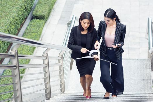 Two businesswomen walking up on stair and talking together. Business and work concept. Job and occupation concept.