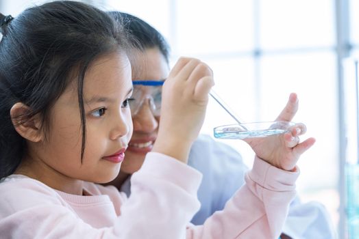 Scientist girl and teacher dropping solution substance liquid with pipette into test tube in lab classroom together. Education and Science. Micro and Nano technology. E-Healthcare and medical concept.