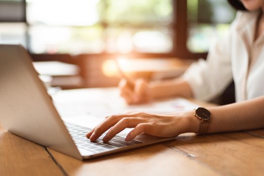 Close up of woman typing keyboard on laptop in coffee shop. People and technology concept. Freelance and Lifestyle theme. Entrepreneur and working outside office theme.