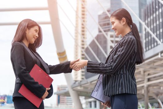 Two business women hand shake at outdoors with traffic background, Business and contact agreement concept