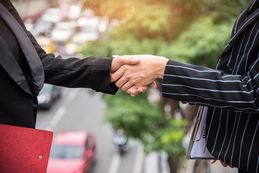 Two business women hand shake at outdoors with traffic background, Business and contact agreement concept