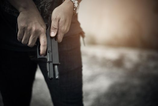 Robber holding gun for ready to murder steal moneys at abandoned building. Selective focus. criminality and social issues concept. Dark and low key tone tone pinterest and instragram like process.