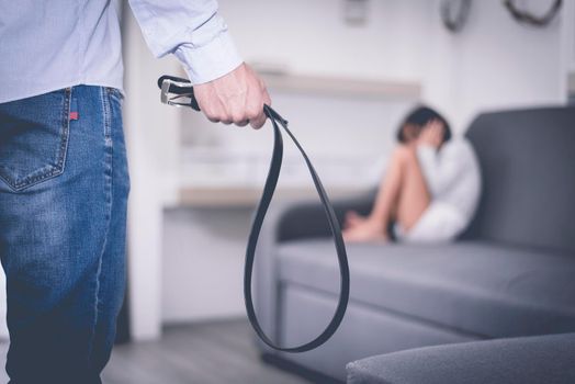 Selective focus of belt in stressed man hand against abstract blur of a little girl fearing in dramatic moment. Children's Rights in Early Childhood Education and Social parents care problem concept
