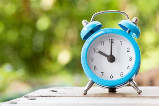 Blue and white Alarm clock on the wood table, Time and Schedule concept