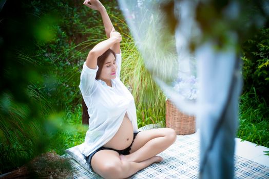 Pregnant woman doing yoga and arm streching at the outdoor, Relax and Health care concept