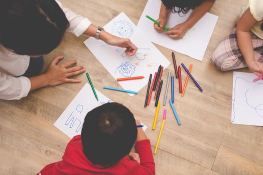 Asian mom teaching four little children to drawing cartoon in art class with color pen. Back to school and Education concept. Family and Home sweet home theme. Preschool kids theme. Top view angle