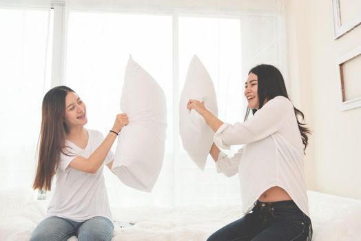 Two Asian girls doing pillow fight in bedroom as childhood. Lifestyles and People concept. Relation and friendship theme. Couple and friends concept. LGBT and people lifestyle