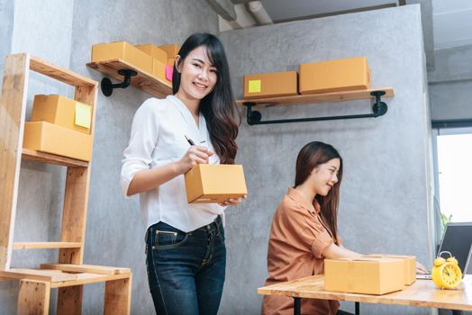 Two young Asian women startup small business entrepreneur SME distribution warehouse with parcel mail box. small  owner home office. Online marketing and product packaging and delivery service
