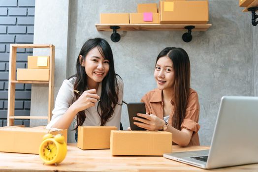 Two young Asian women startup small business entrepreneur SME distribution warehouse with parcel mail box. small  owner home office. Online marketing and product packaging and delivery service