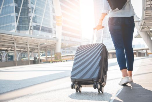 Female traveler tourist walking with luggage at terminal station. Activity and lifestyle concept. Business people and long holiday vacation theme. Back view