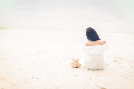 Asian woman waiting for love or somethings that make her happy. Lonely and Beauty concept. Back view scene of girl. Ocean and sea theme. Copy space in left side. Soulmate theme.