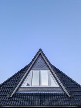 Open roof window in velux style with black roof tiles