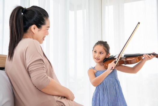 Girl playing violin with her pregnant mother for lullaby newborn in mother belly. Musical and entertainment concept.