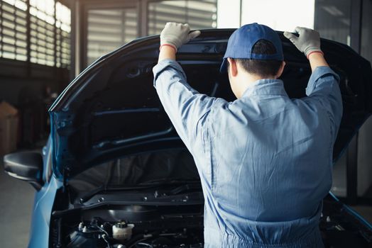 Car mechanic opening car hood for internal checking to maintenance vehicle by customer claim order in auto repair shop garage. Engine repair service. People occupation and job. Automobile technician