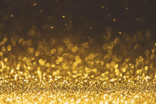 Gold glitter sparkle lights background. Defocused glitter abstract twinkly light and shiny stars. Christmas and New year party concept background. Closeup stardust. 