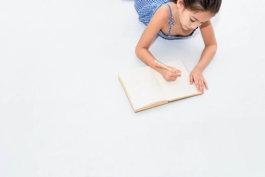 Top view of happiness girl drawing in sketch book on white floor at home or nursery. People lifestyle and kids play. Education and Children concept. Back to school theme. Copy space background