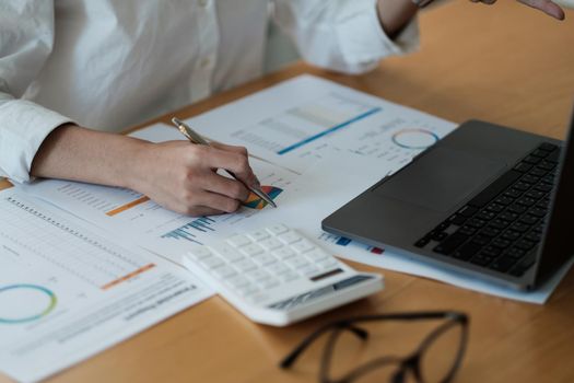 Woman accountant use calculator and computer analytic marketing report on wooden desk in office. finance and accounting concept