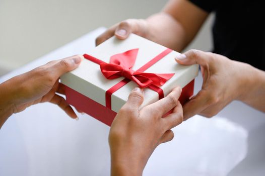 Closeup of hands giving gift box in Christmas day and new year festival to each other. Holiday and event. Surprising giftbox in dating on end year party. People lifestyle and object concept.