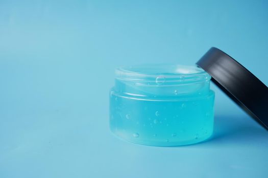 a jar of hair gel on blue background with copy space .
