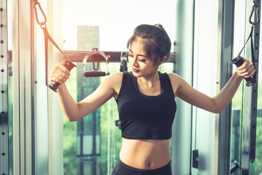 Asian young woman doing elastic rope exercises at cross fitness gym. Strength training and muscular. Beauty and Healthy concept. Sport equipment and Sport club center theme. 