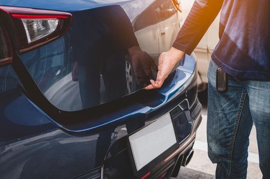 Closeup of man hand opening hatchback trunk by touching sensor door. People lifestyle and transportation technology. Travel and road trip concept. Automotive transportation and outdoors theme
