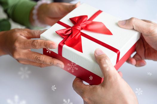 Closeup of hands giving gift box in Christmas day and new year festival to each other. Holiday and event. Surprising giftbox in dating on end year party. People lifestyle and object concept.