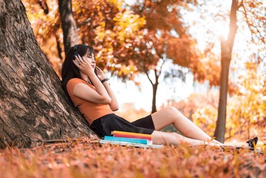 Asian beauty woman listen to the music in park. People lifestyles and Entertainment concept. Relaxation and Vacation concept. Autumn and fall seasonal theme.