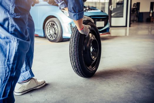 Car mechanics changing tire at auto repair shop garage. Transportation and Business working people concept. Automobile technician maintenance vehicle by customer claim order. Wheel repair service