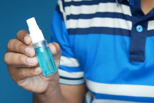 hand hold a mouthwash liquid container against blue background .