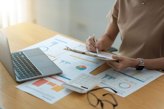 Cropped accountants work analyzing financial reports on a laptop at his office, business analytics concept