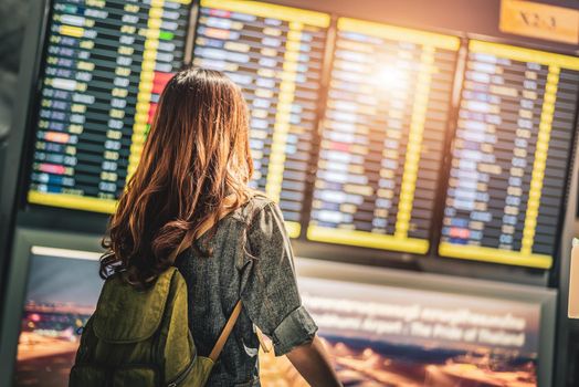 Beauty female tourist looking at flight schedules for checking take off time. People and lifestyles concept. Travel and Happy life of single woman theme. Back view portrait.