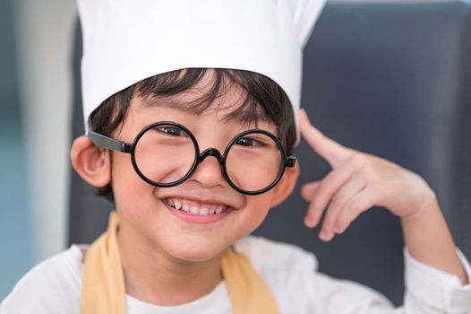 Portrait cute little Asian happiness boy interested in cooking with mother funny in home kitchen. People lifestyles and Family. Homemade food and ingredients concept. Baking Christmas cake and cookies