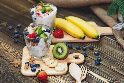 Healthy Greek yogurt with Granola and mixed berries on wooden table and many fruits. Food and dessert concept.