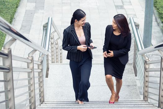 Two businesswomen walking up on stair and talking together. Business and work concept. Job and occupation concept.