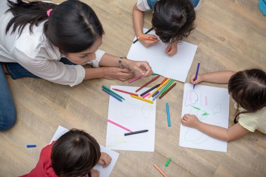 Group of preschool student and teacher drawing on paper in art class. Back to school and Education concept. People and lifestyles theme.  Room in nursery