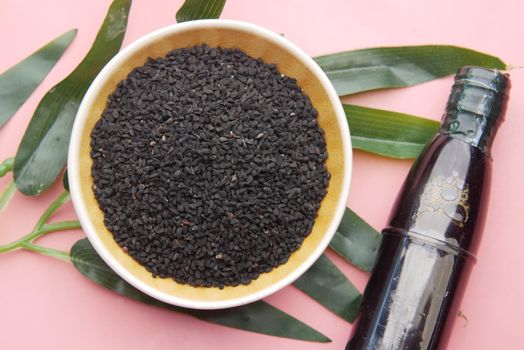 Black Cumin in container with oil in a jar on table