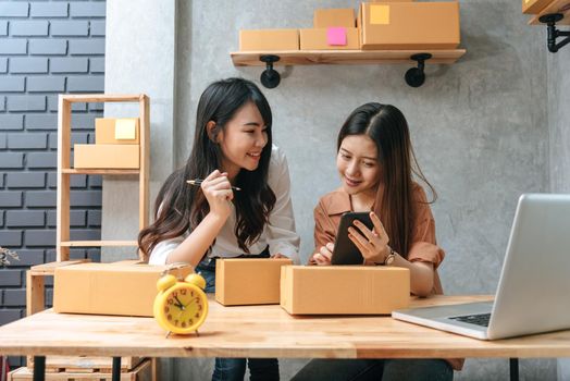 Two young Asian women startup small business entrepreneur SME distribution warehouse with parcel mail box. small  owner home office. Online marketing and product packaging and delivery service