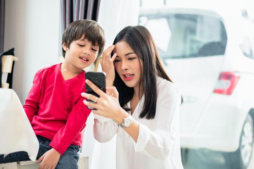 Mom and her child using and looking into smartphone together. People and Technology concept. Education and Learning theme.