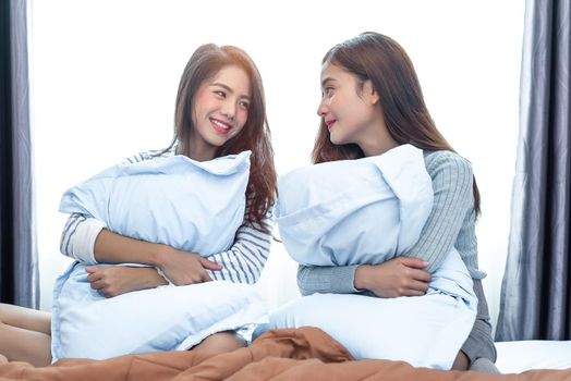 Two Asian Lesbian looking together in bedroom.Beauty concept. Happy lifestyles and home sweet home theme. Cushion pillow element and window background.