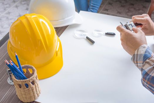 Construction engineer measuring with vernier caliper. Business and Technology concept. Safety helmet and Drawing paper elements. Civil and Drawing sketch theme.