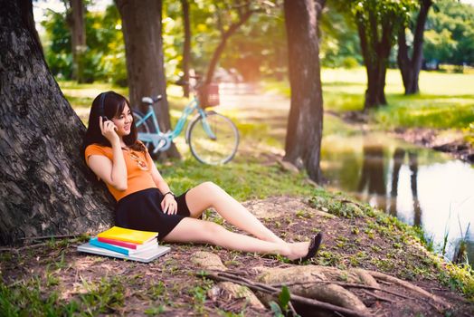 Woman relax under the tree in the park with headphones, relax concept