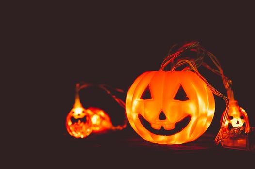 Halloween pumpkin and light in dark, wooden background. Halloween festival celebration concept. Low key toned. Copy space