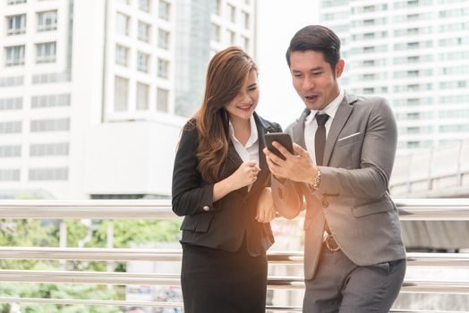 Two businessman and woman enjoy using mobile phone. Relax time and Happiness concept.