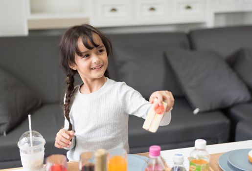 Happy little girl giving sandwich cooking toy as chef in living room. Playful of child and happiness education and development concept. Learning and leisure of cute girl. Nursery and daycare theme.