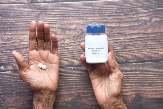 senior women hand hold covid 19 medical medial pills on table .