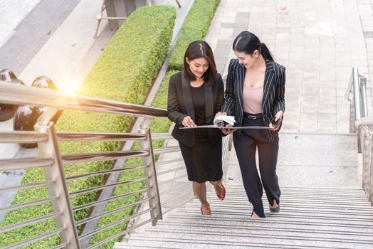 Two businesswomen walking up on stair and talking together. Business and work concept. Job and occupation concept.