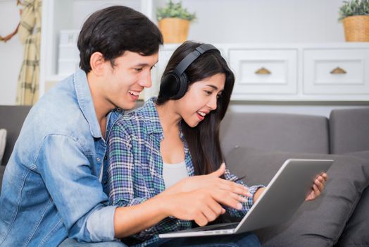Lovers or couple using laptop and listening music with headphone in house. Honeymoon and Entertainment concept. Happiness and lifestyle concept. Communication technology and people in sweet home theme